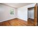 This cozy bedroom features hardwood floors, a window, neutral walls, and a door to another room at 542 9Th Nw St, Hickory, NC 28601