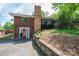 Side view of brick home with a stone chimney, front yard landscaping, and two red doors at 542 9Th Nw St, Hickory, NC 28601