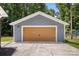 A detached gray garage featuring a double wide door, perfect for storage or a workshop, sits on a concrete pad at 7141 Pitchfork Ln, Mint Hill, NC 28227