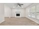 Bright living room featuring wood-look floors, a modern ceiling fan, and a cozy painted white brick fireplace at 7141 Pitchfork Ln, Mint Hill, NC 28227