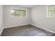 Bright bedroom features natural light from two windows, gray laminate flooring, and freshly painted gray walls at 816 Echo Glen Rd, Charlotte, NC 28213