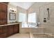 Luxurious bathroom with a tub, a glass shower, and travertine tile at 9217 Rock Water Ct, Waxhaw, NC 28173