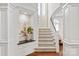 Bright foyer with an elegant staircase featuring white wood trim, a display niche and hardwood floors at 9217 Rock Water Ct, Waxhaw, NC 28173