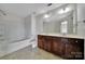 Bright bathroom featuring a double vanity, large mirror, and tub with shower at 9862 Walkers Glen Nw Dr, Concord, NC 28027