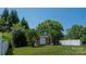 Backyard with a shed, green grass, bushes, trees, and a white fence at 1004 Toquima Trl, Monroe, NC 28110