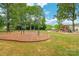 Neighborhood playground with swings and a modern climbing structure with slides surrounded by mature shade trees at 1004 Toquima Trl, Monroe, NC 28110