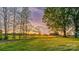Sunset view over green property with mature trees and outbuildings at 153 Coachman Loop, Statesville, NC 28625