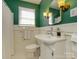 Cozy bathroom featuring green walls, tiled floors, vanity, commode and decorative wall sconces at 1596 Clayton Dr, Charlotte, NC 28203