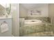Bright bathroom featuring an oval soaking tub with tile surround and decorative floral wall art at 1596 Clayton Dr, Charlotte, NC 28203