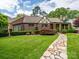 Charming brick home with a stone walkway, manicured lawn, and lush landscaping at 1596 Clayton Dr, Charlotte, NC 28203