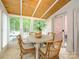 Bright sunroom with many windows, wood ceiling, tile floors, and a white dining table with seating at 1596 Clayton Dr, Charlotte, NC 28203