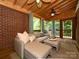 Cozy sunroom with brick wall, vaulted wood ceiling, and comfortable seating area at 1596 Clayton Dr, Charlotte, NC 28203