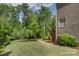 Spacious backyard featuring green grass, trees, brick house, and small wooden deck at 16519 Flintrock Falls Ln, Charlotte, NC 28278