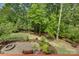 Landscaped backyard with fire pit and natural stone patio featuring wooded surroundings at 16519 Flintrock Falls Ln, Charlotte, NC 28278