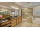 Bathroom with dual vanities, large mirror, tiled shower, and soaking tub at 16519 Flintrock Falls Ln, Charlotte, NC 28278