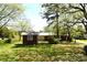 A view of the backyard featuring a vibrant green lawn and a small outbuilding nestled among the trees at 17389 Mooresville Rd, Mooresville, NC 28115