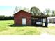 Rustic barn with weathered red siding and covered parking area, surrounded by a green lawn at 17389 Mooresville Rd, Mooresville, NC 28115