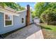 Home exterior showcasing a brick chimney, blue siding, and a driveway leading to a detached garage at 1938 Dembrigh Ln, Charlotte, NC 28262