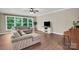 Bright living room featuring hardwood floors, neutral-colored furniture, and large windows with backyard views at 2417 Labelle Dr, Waxhaw, NC 28173