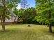Home showcasing the expansive, verdant backyard with mature trees, deck, and well-maintained lawn at 3179 Westview Rd, Concord, NC 28025