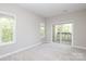 Bright bedroom features neutral carpet, a large window, and a sliding glass door to a balcony at 3937 Arbor Ln # H, Charlotte, NC 28209