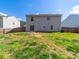 View of the home's rear exterior and spacious backyard with a well-maintained lawn and privacy fence at 4018 Larkhaven Village Dr, Charlotte, NC 28215