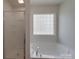 Close up of a tub with glass block window and a glass shower door at 4018 Larkhaven Village Dr, Charlotte, NC 28215