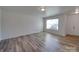 An empty living room featuring light walls, light laminate flooring, and ample natural light from an unseen window at 4018 Larkhaven Village Dr, Charlotte, NC 28215
