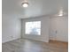 An empty living room with light walls, light laminate flooring, and ample natural light from an unseen window at 4018 Larkhaven Village Dr, Charlotte, NC 28215