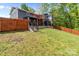View of the home's back yard with a wooden fence, lush grass, patio, and stairs at 4050 Leafmore St, Concord, NC 28027