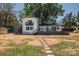 Charming waterfront home featuring a spacious deck and stepping stone pathway to the lawn at 451 S Strand Dr, Norwood, NC 28128