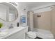 Bright bathroom featuring a round mirror, neutral tiled shower and a white single sink vanity at 505 N Graham St # 2H, Charlotte, NC 28202