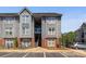 Exterior view of a multi-story condo building with gray siding, brick accents, and ample parking at 505 N Graham St # 2H, Charlotte, NC 28202