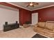 Cozy living room with red walls, tan carpet, ceiling fan, sofa, and a media center at 505 S South St, Gastonia, NC 28052