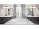 Bright bathroom showcasing a large soaking tub, marble surround, and dual vanity sinks at 5051 Hyannis Ct, Matthews, NC 28104