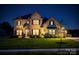 Two-story brick home with a well-manicured lawn and beautiful landscaping at dusk at 5051 Hyannis Ct, Matthews, NC 28104