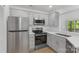 Updated kitchen features stainless steel appliances, gray cabinets with gold pulls, and granite countertops at 6523 Clavell Ln, Charlotte, NC 28210