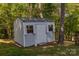 Utility shed in the backyard, painted white with a shingled roof and side windows at 8044 Eagle St, Mount Pleasant, NC 28124