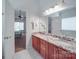 Bathroom showcasing a double vanity with granite counters, a large mirror, and views into an adjoining bedroom at 8623 Cedar Hollow Ln, Huntersville, NC 28078