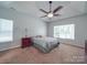 Spacious bedroom featuring neutral carpet, tray ceiling with ceiling fan, a large window, and a decorative dresser at 8623 Cedar Hollow Ln, Huntersville, NC 28078