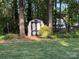 Backyard storage shed surrounded by trees and green grass, offering extra storage space at 8623 Cedar Hollow Ln, Huntersville, NC 28078