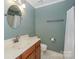 Bright bathroom featuring a wood vanity with a white sink, with an oval mirror and a tiled floor at 867 Southwest Dr, Davidson, NC 28036
