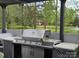 This outdoor kitchen features granite countertops, a stainless steel grill, and a serene backyard view at 9535 Potter Rd, Matthews, NC 28104