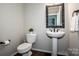 Well-lit half-bathroom featuring a sleek pedestal sink, toilet, and dark-themed accents at 9860 Darby Creek Nw Ave, Concord, NC 28027