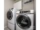 Laundry room equipped with modern front load washer and dryer units, plus overhead shelving at 9860 Darby Creek Nw Ave, Concord, NC 28027