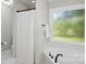 Clean bathroom featuring a shower with curtain, tub, updated fixtures, and a frosted window at 1305 Foxfield Rd # 60, Waxhaw, NC 28173