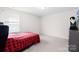Bright bedroom with neutral walls and carpet, plus a large window for natural light and a mannequin with a black dress at 13547 Roderick Dr, Huntersville, NC 28078