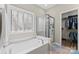 Bright bathroom featuring a soaking tub, glass enclosed shower and a view into the walk-in closet provides a spa like experience at 15744 Berryfield St, Huntersville, NC 28078