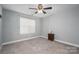 Bedroom features neutral carpet, a ceiling fan, a window for natural light, and a side table at 2388 Loch Stone Dr # E, Gastonia, NC 28054