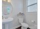 Clean half bathroom featuring pedestal sink, toilet, and a window providing natural light at 2551 Statesville Ave, Charlotte, NC 28206